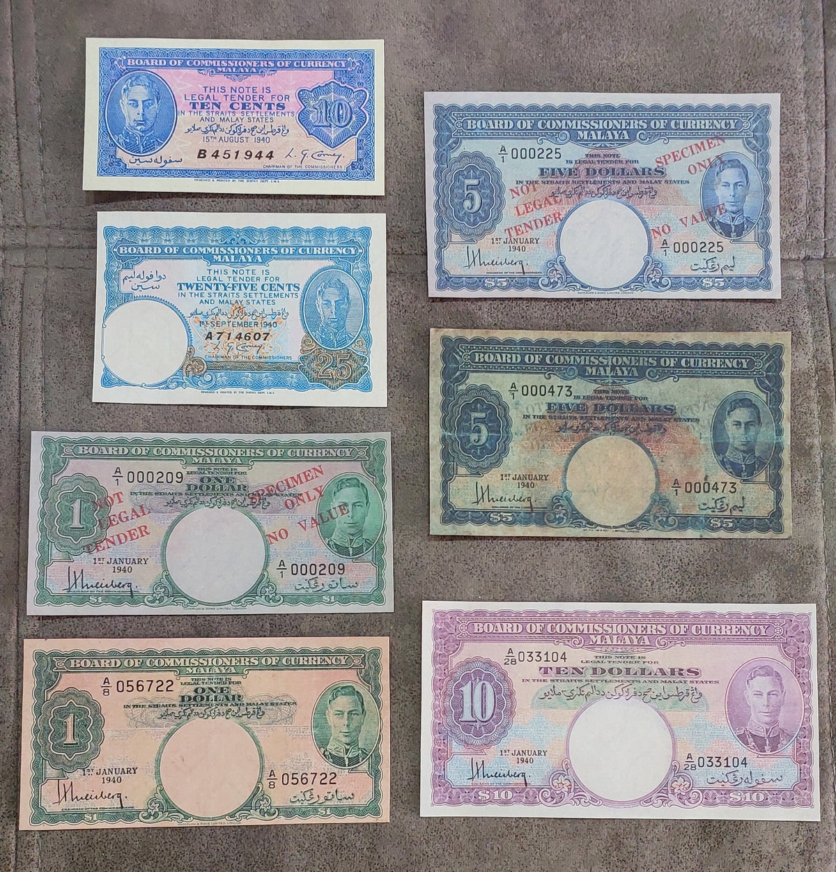 Full lot overview displaying all 7 historical Malayan banknotes (1940) arranged in a grid showing reverse side artwork and circular watermark windows